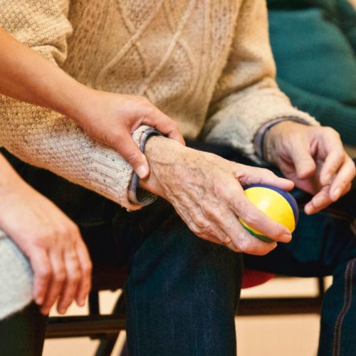 pexels-photo-339620-339620-1 An elderly person receives support from a caregiver, holding hands indoors, showcasing compassion.